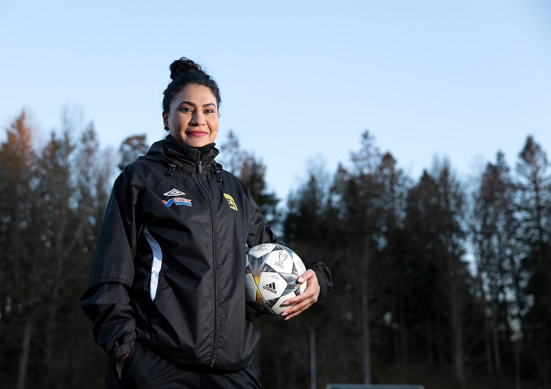 kvinna står med en fotboll i handen