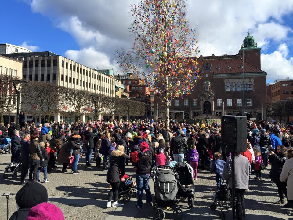 Påskfirande runt ett träd med fjädrar på ett torg