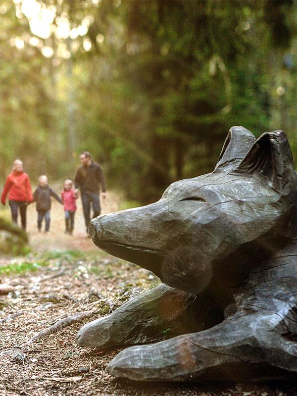 En familj i bakgrunden och en räv i trä i förgrunden-