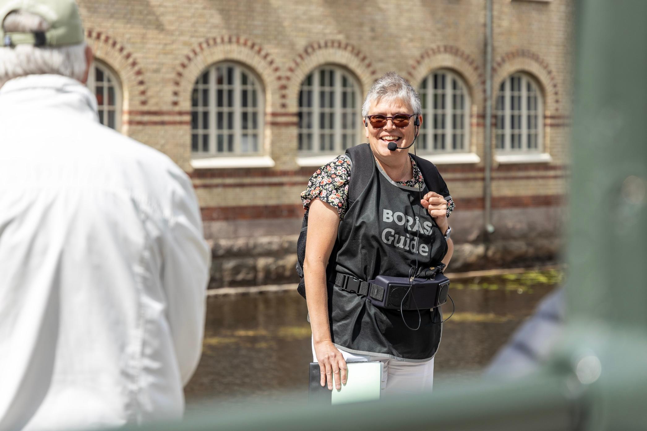 En guide pratar framför en folksamling.