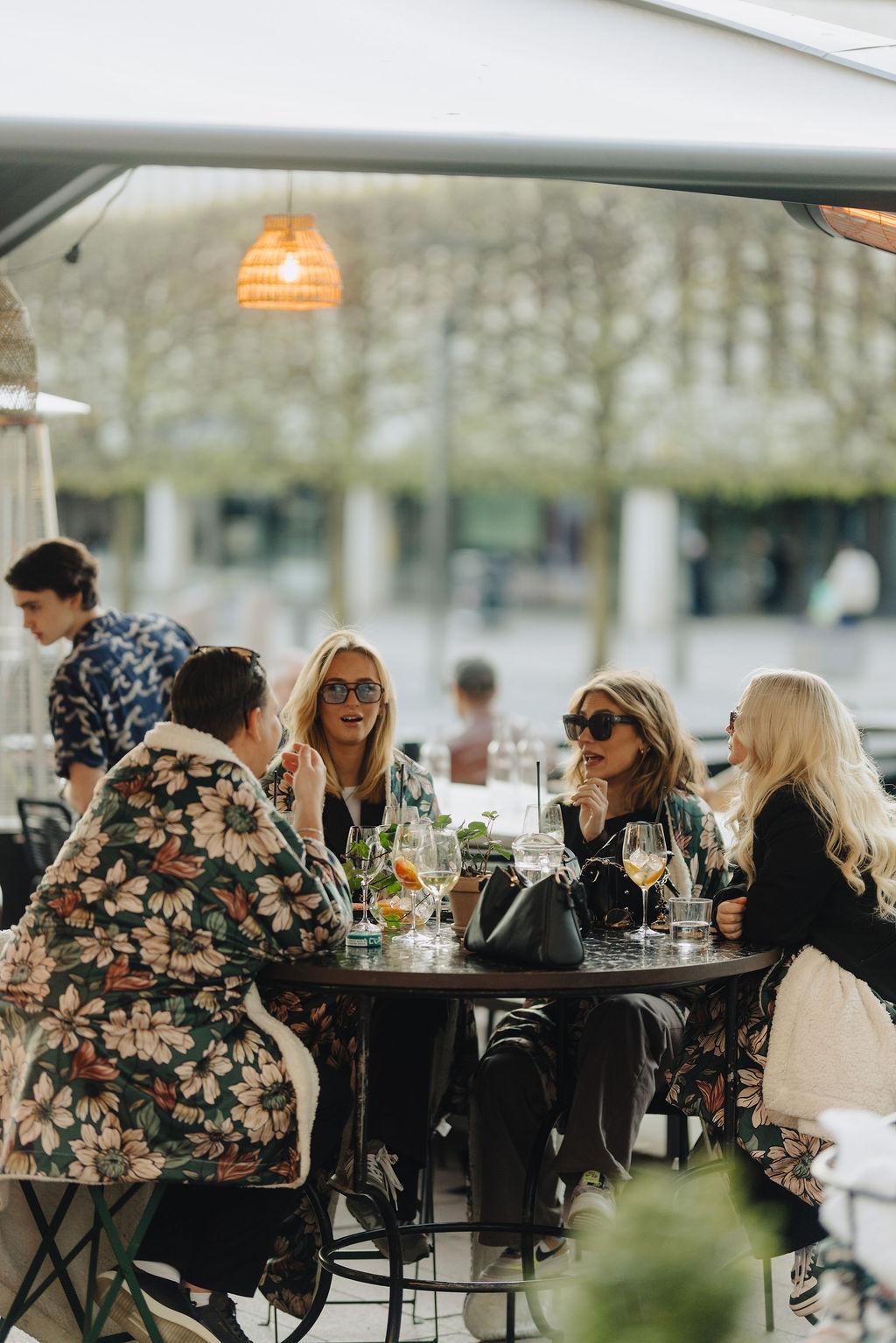 En grupp tjejer sitter runt ett bord på en uteservering.