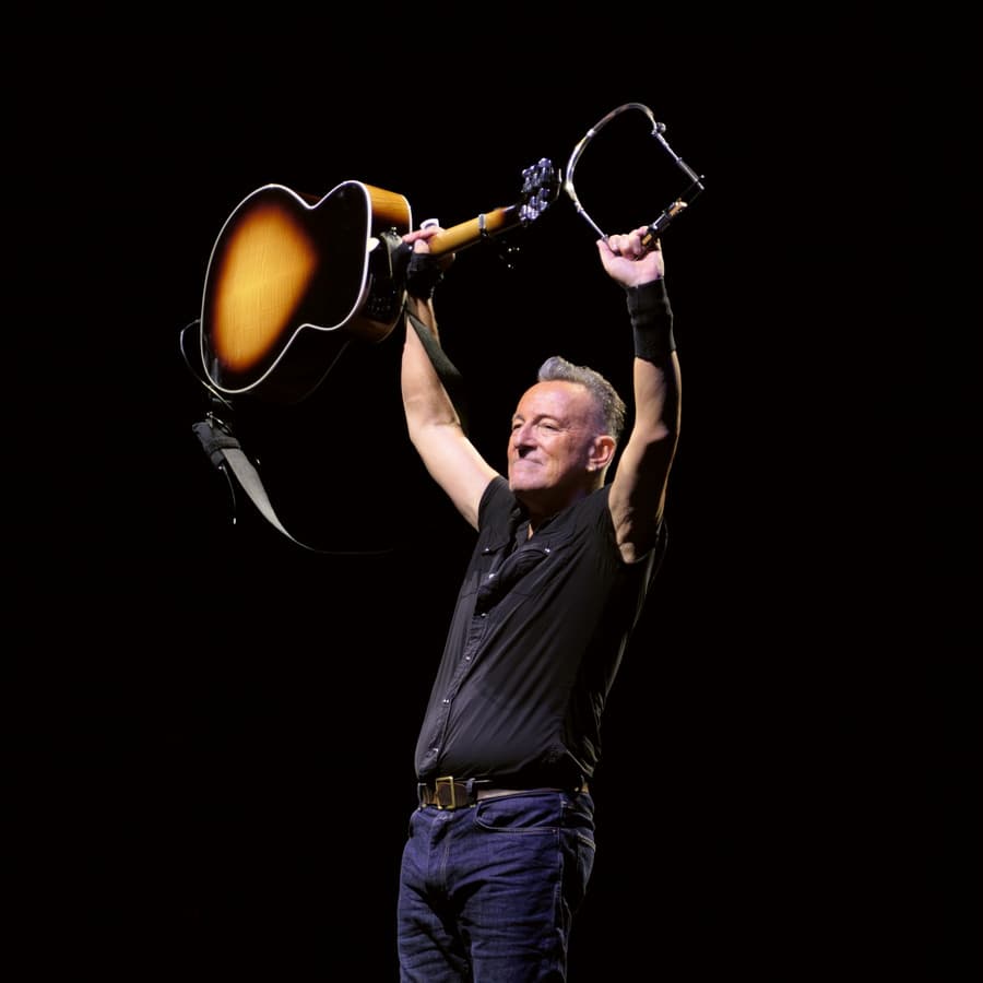 Bruce Springsteen lyfter en gitarr i luften.