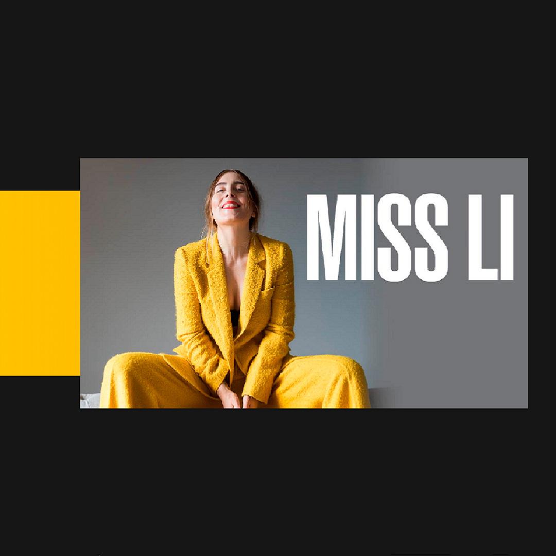 Miss Li i gula kläder. Sitter på en bänk och ser glad ut.